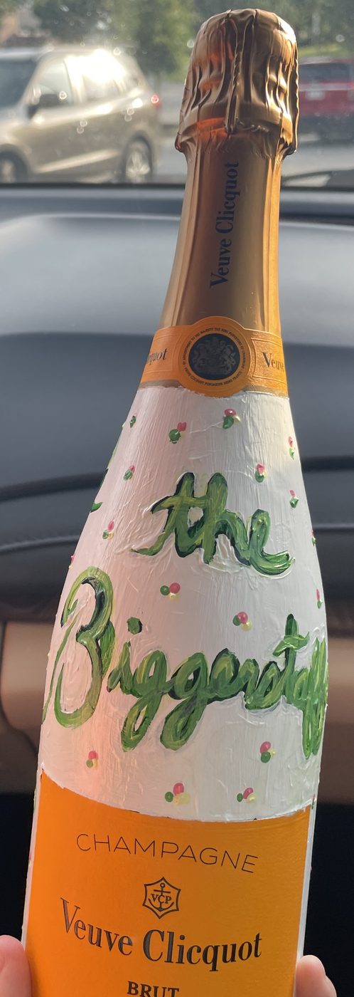 Hand-painted white champagne bottle with green lettering, reading the Biggerstaffs